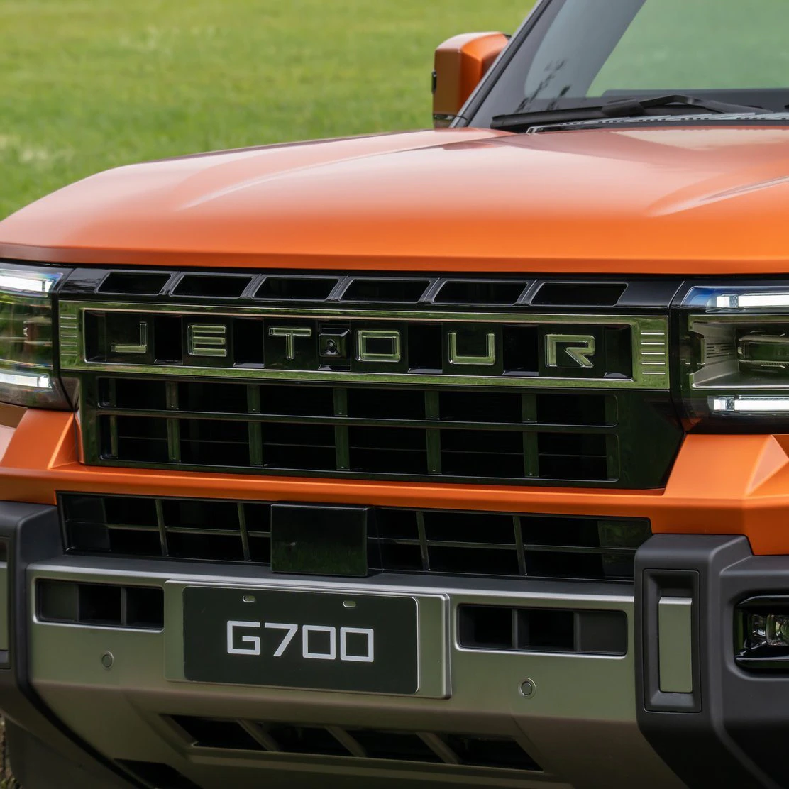 Grade frontal do JETOUR G700 laranja com o nome JETOUR e o emblema G700